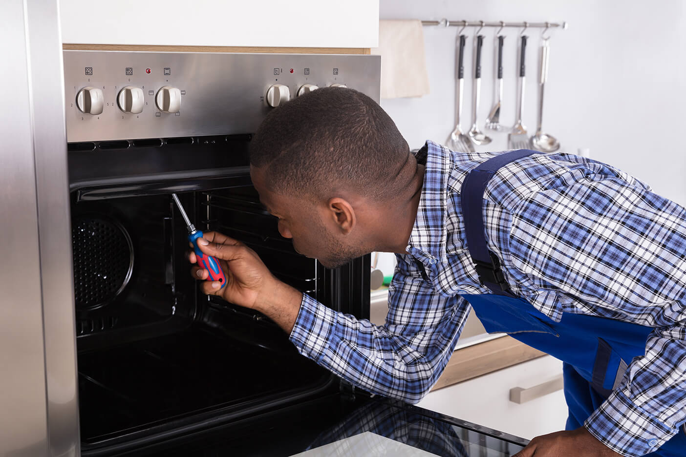 Man fixing stove with a screwdriver